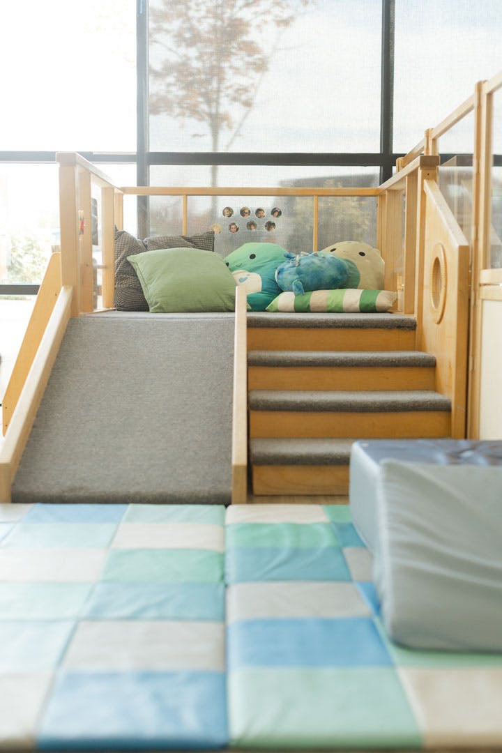 Small wooden indoor play structure with a slide and stairs