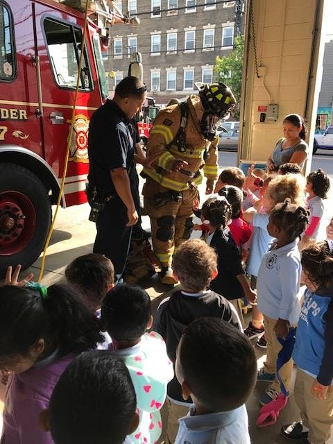 Firefighter in full gear interacting with a group of children near a fire truck