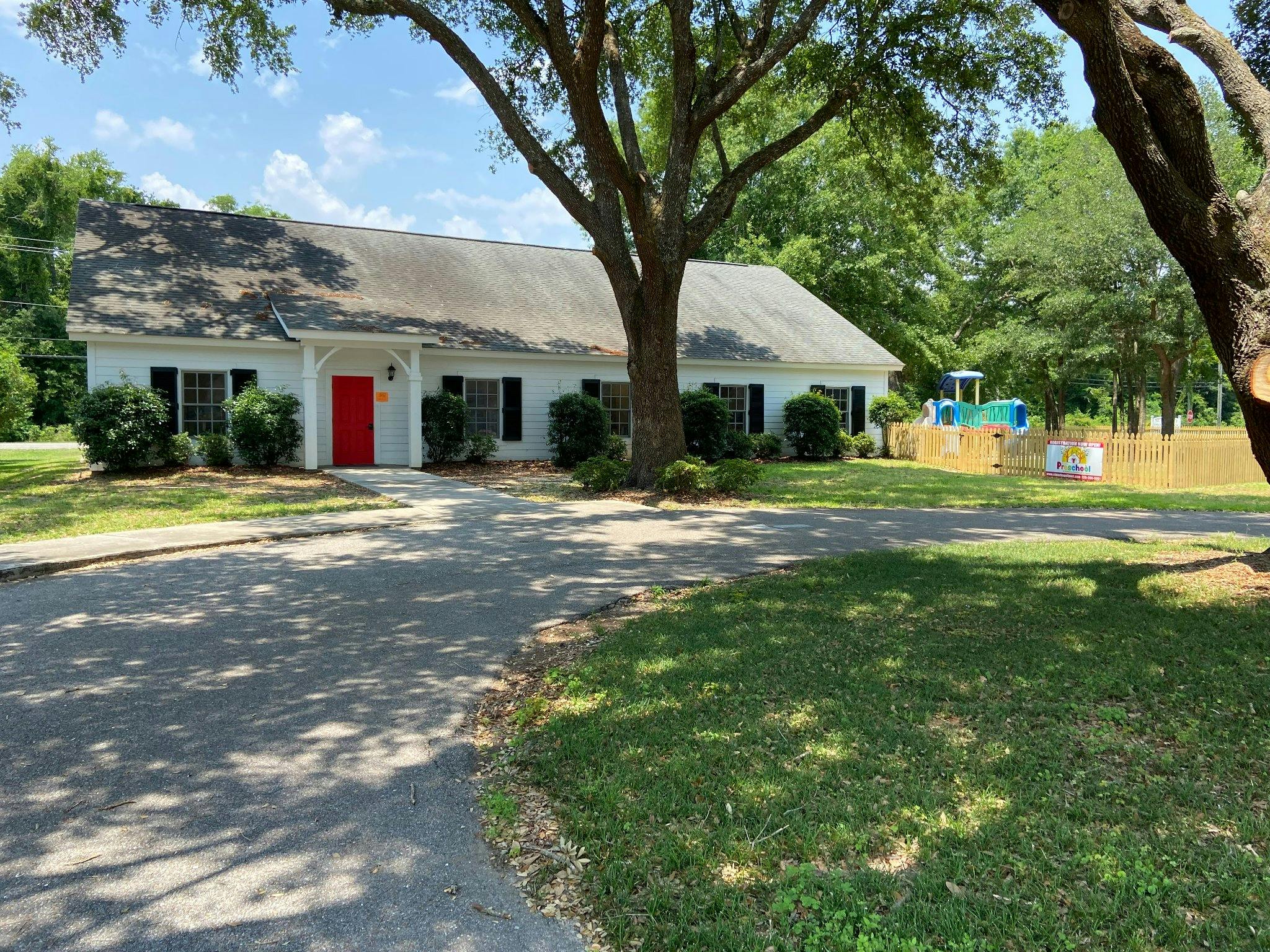 White building with a red door and a playground in the background