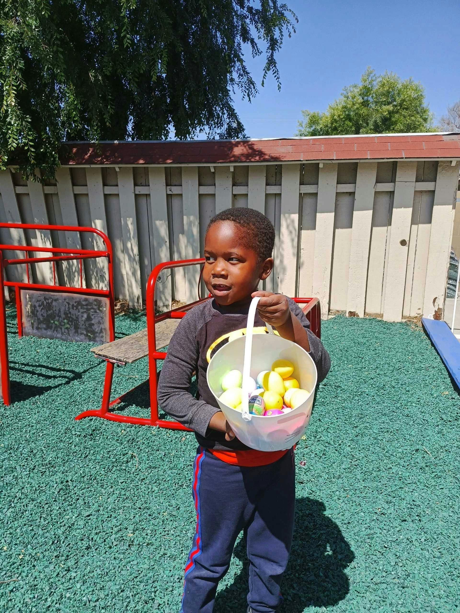 Child holding a basket of plastic eggs on a playground