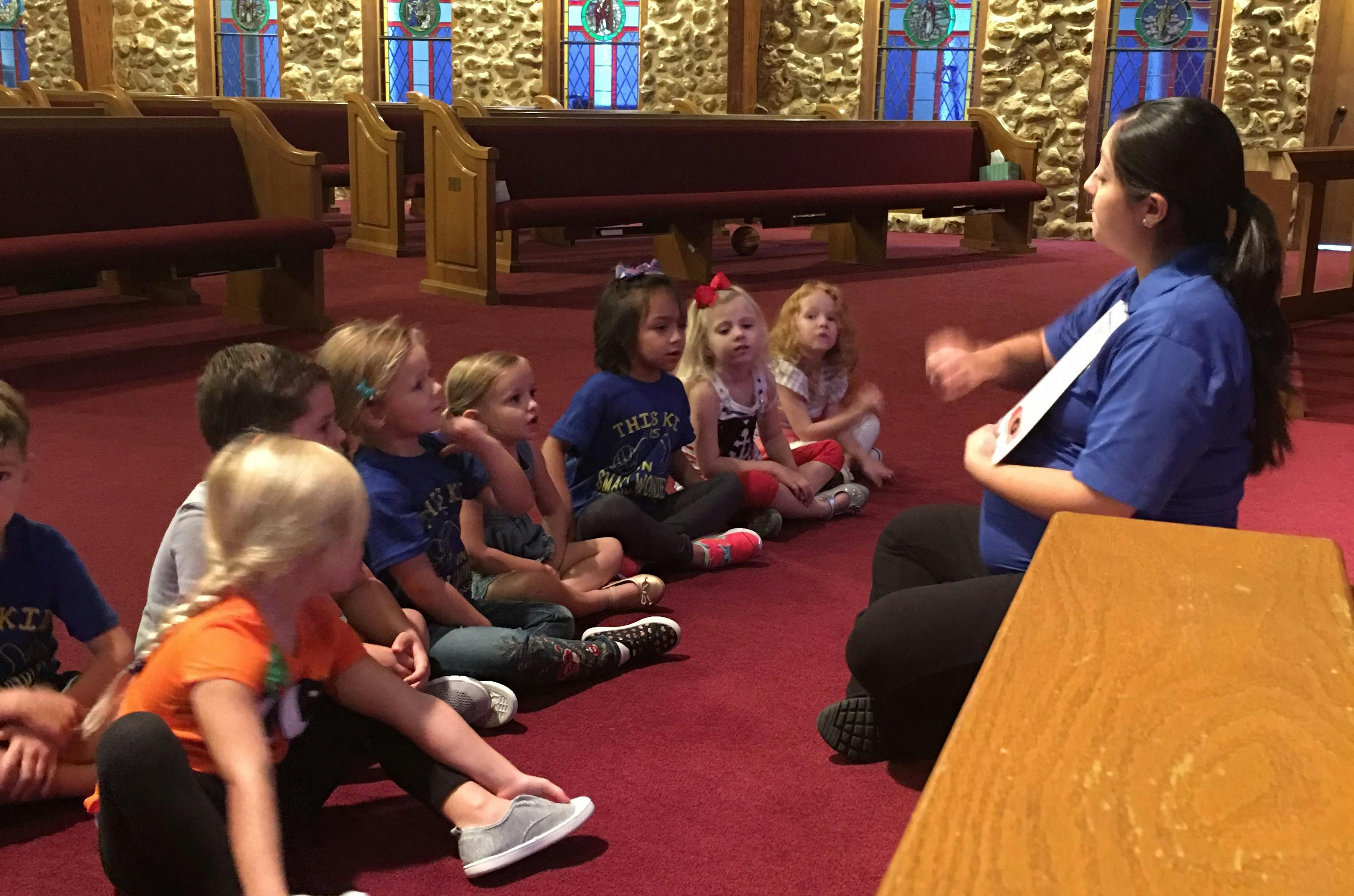 Adult person reading to a group of children sitting on the floor
