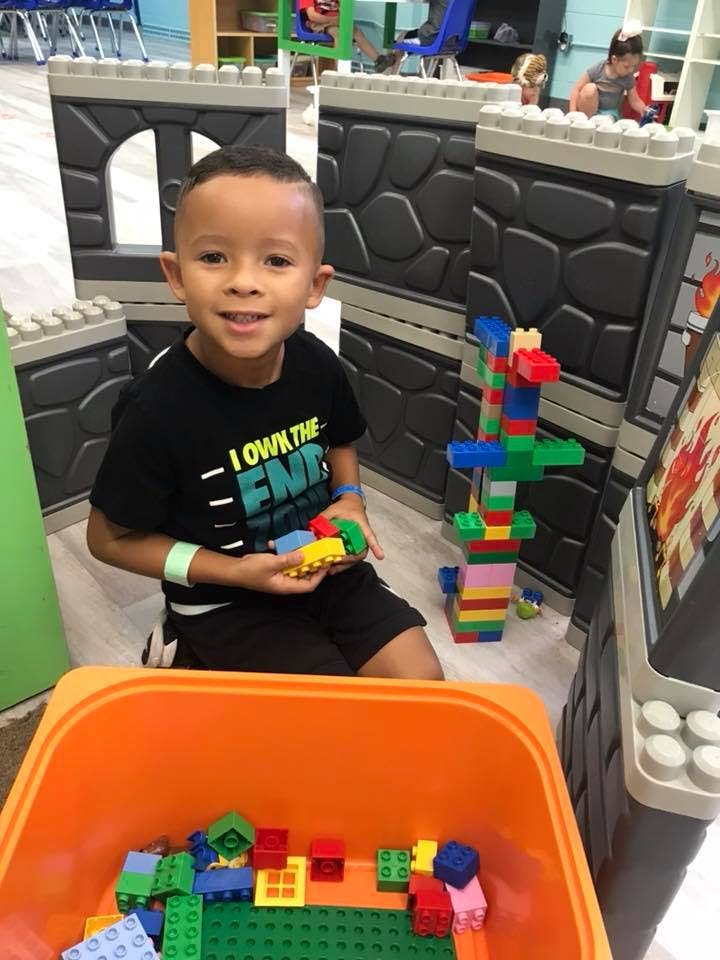 Child kneeling and holding building blocks