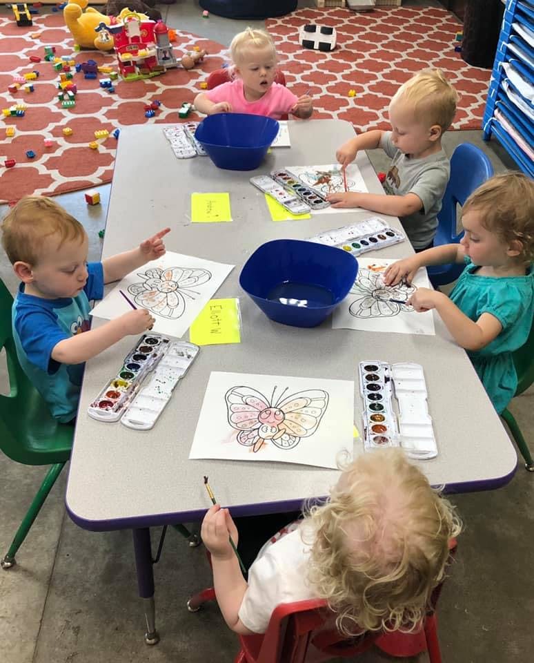 Children painting butterfly pictures at a table