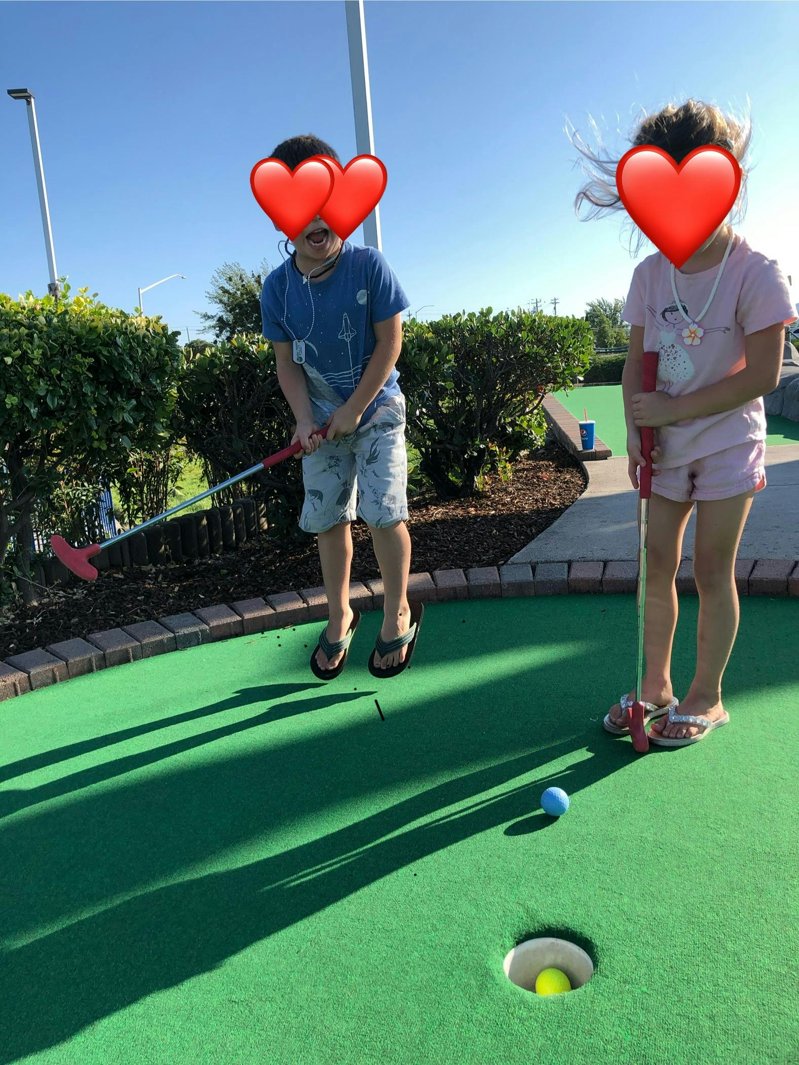 Two children playing miniature golf on an outdoor course