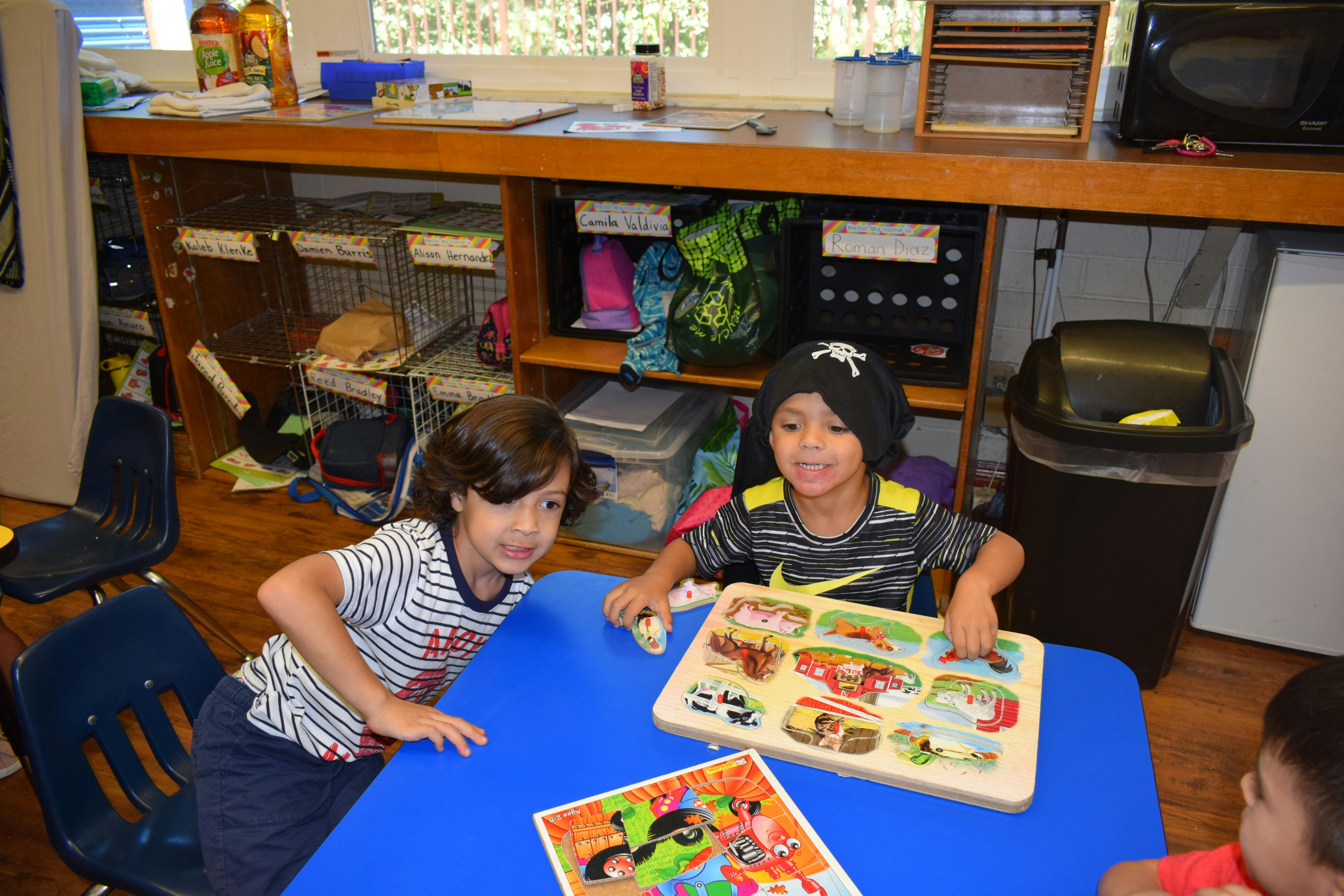 Two children playing with puzzles at a blue table