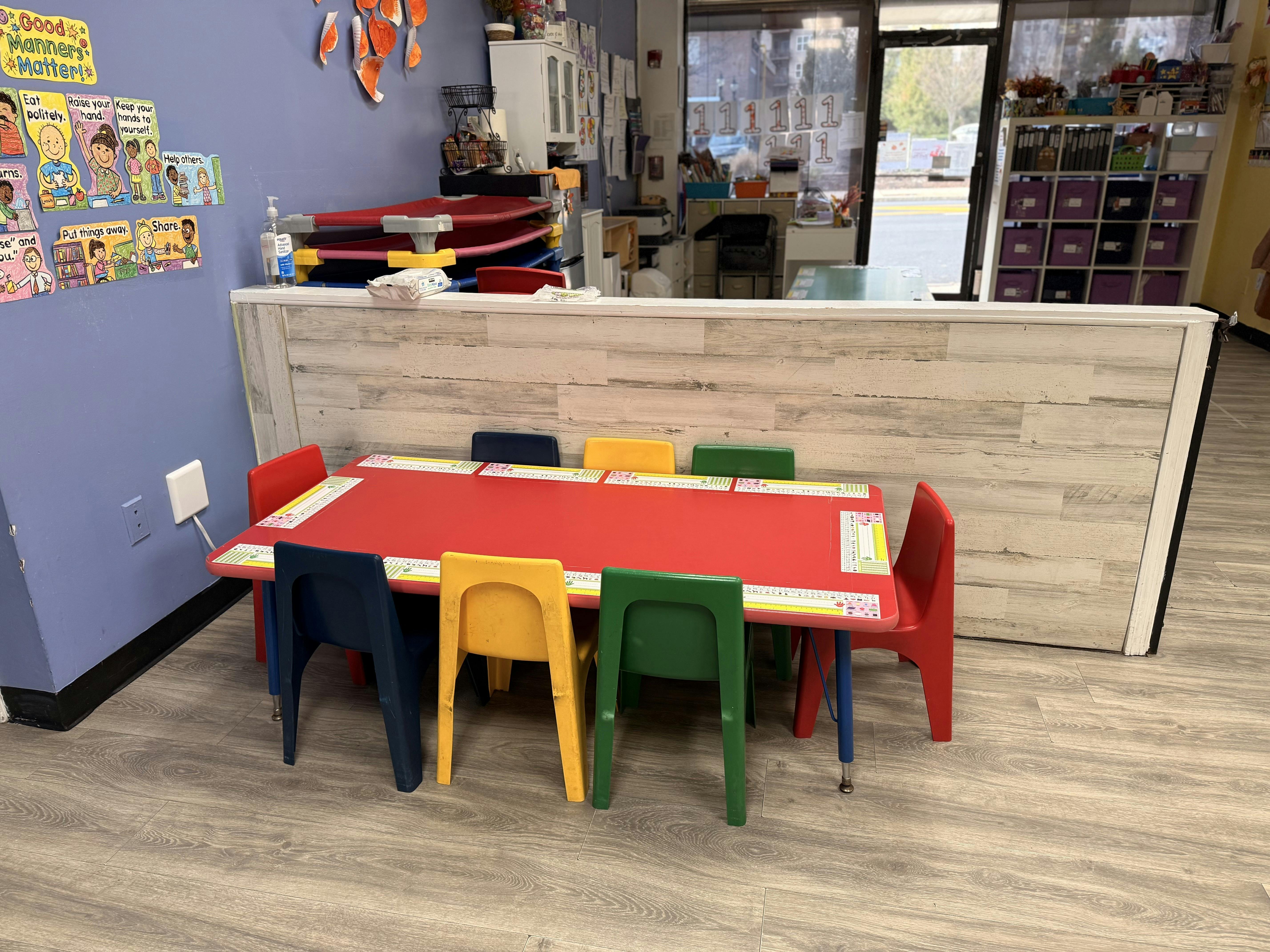 Red children's table with colorful chairs in a classroom