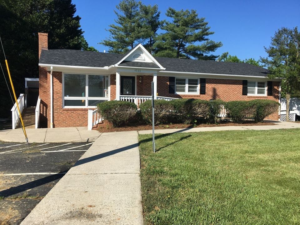 Brick building with a white porch and a sidewalk leading to it