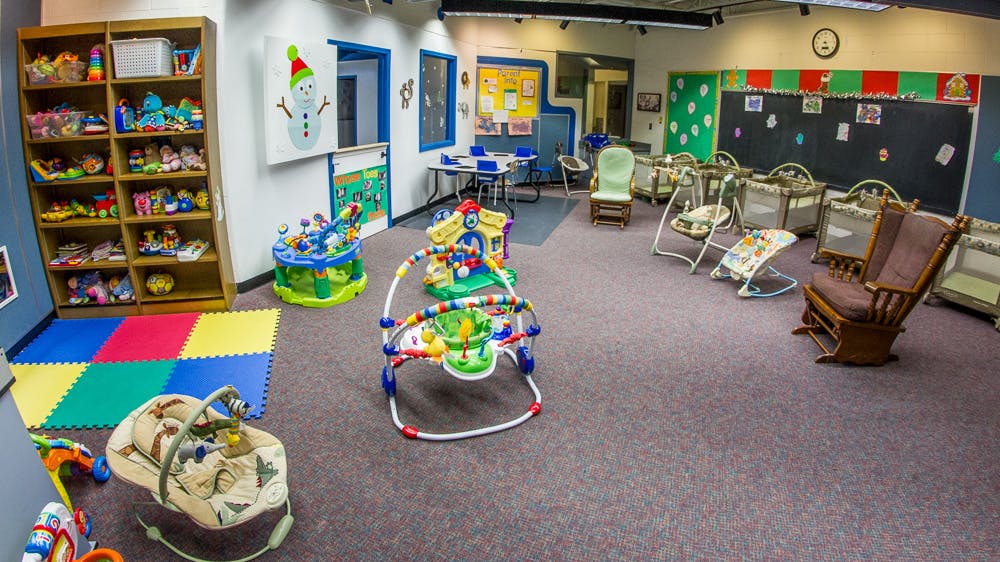 Childcare room with play mats, toys, and infant swings