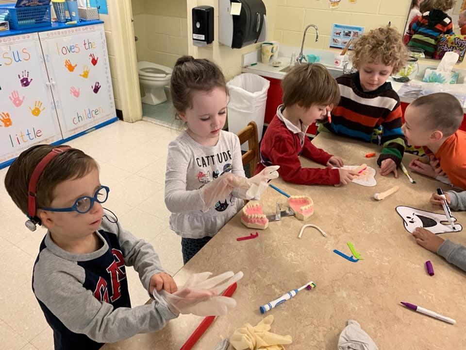 Children at a table putting on gloves and looking at dental models