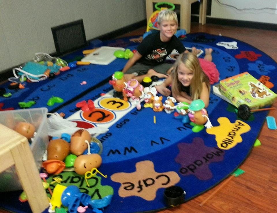 Two children playing with toys on a blue rug