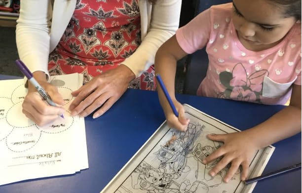 Person and child drawing and coloring at a table