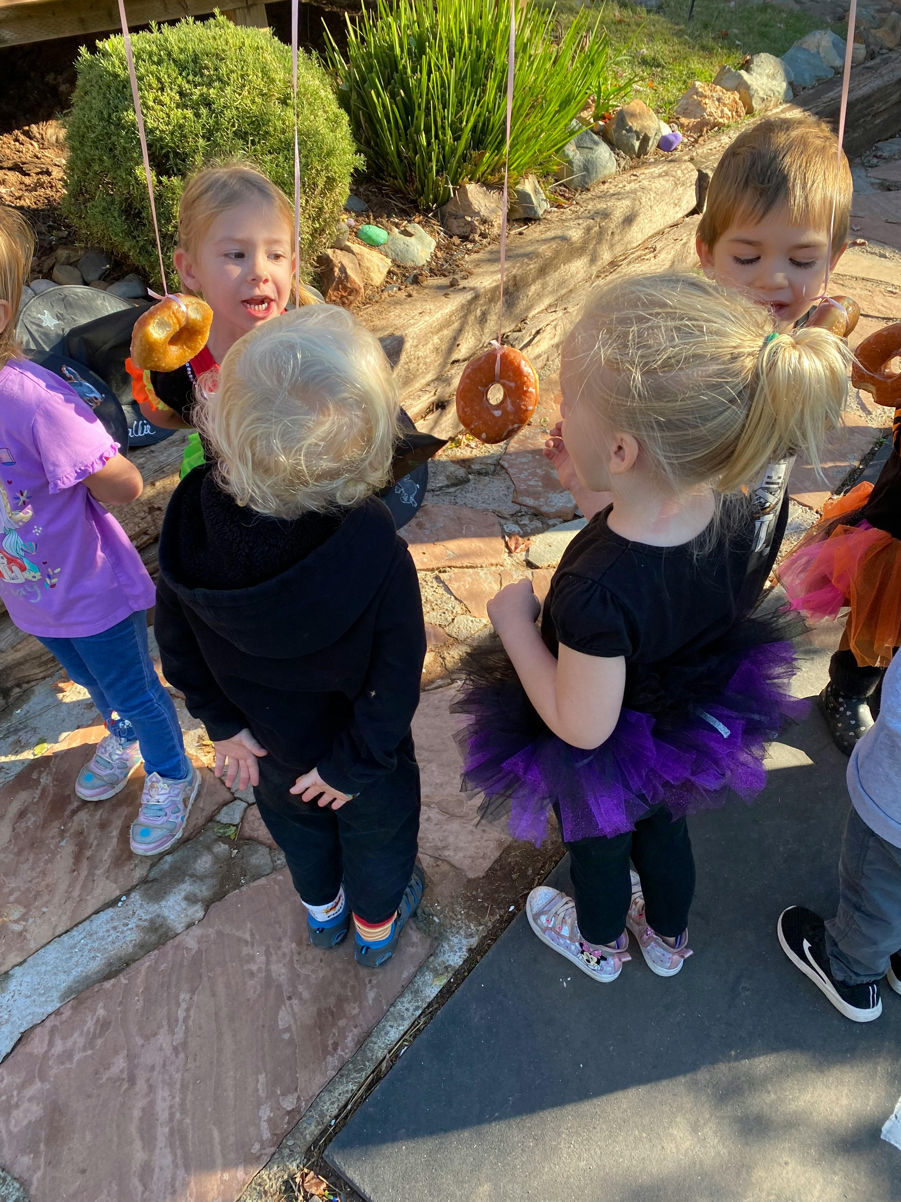 Children playing a game with hanging donuts