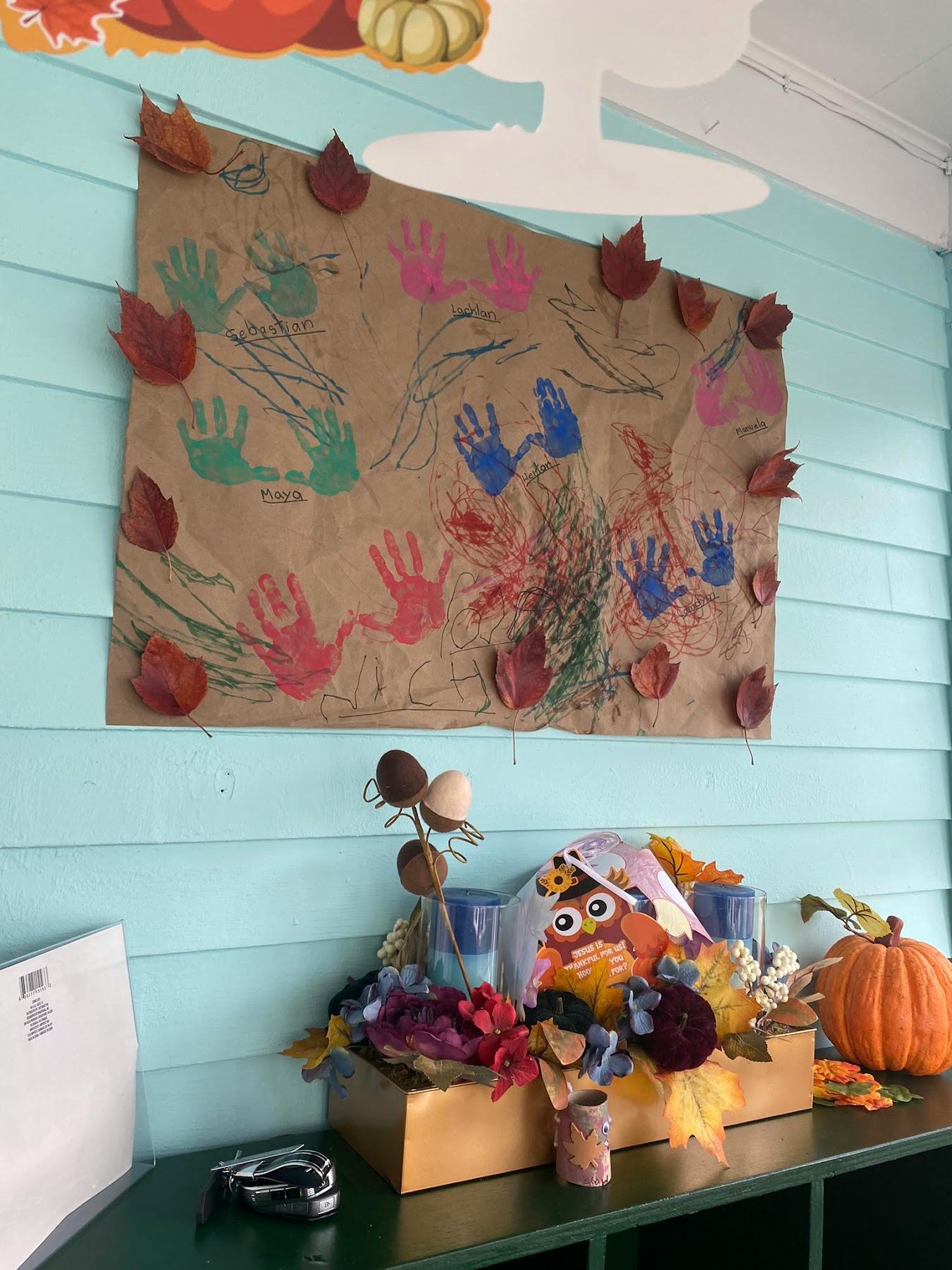 Childrens handprint art on brown paper decorated with fall leaves