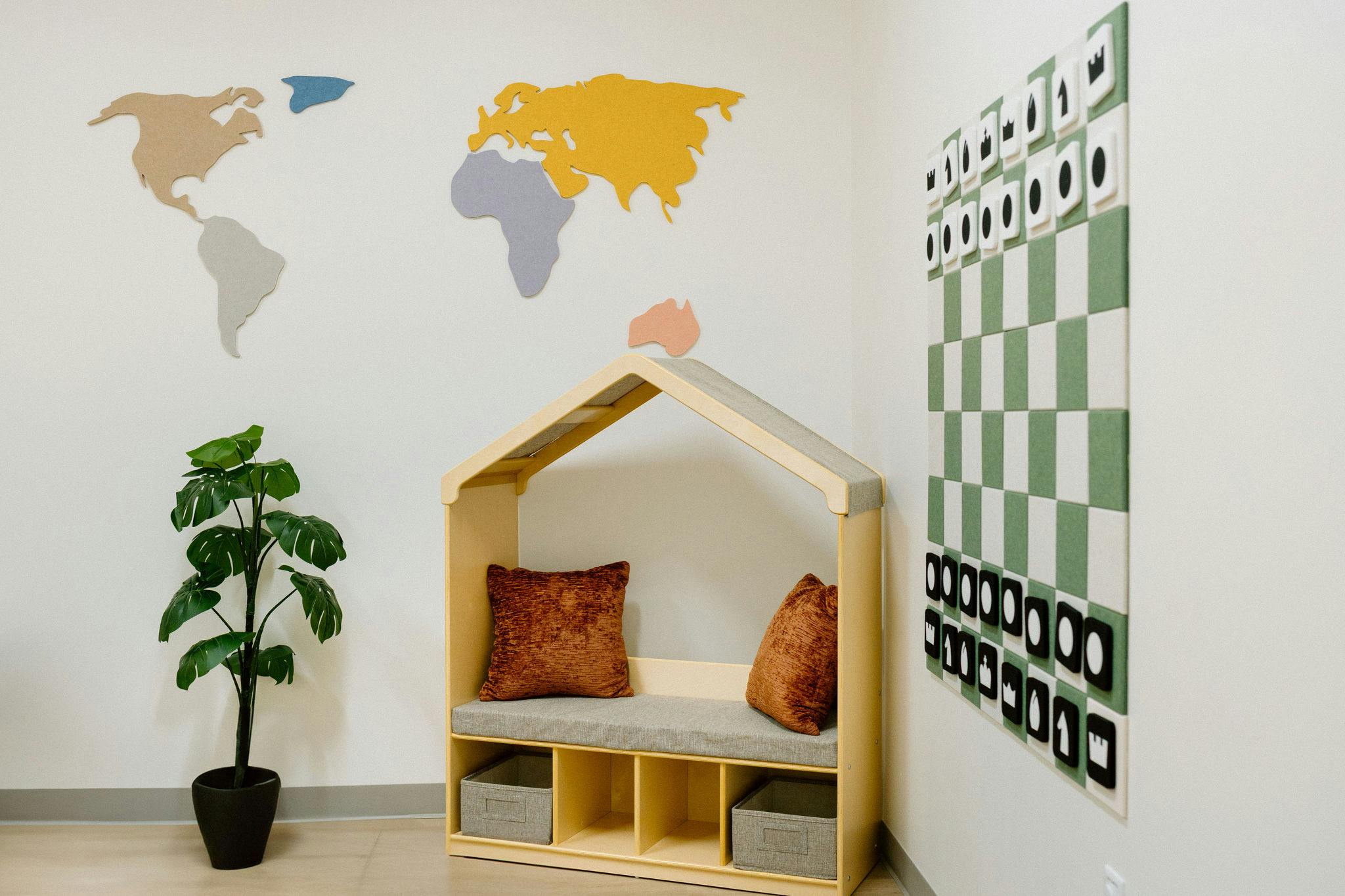 Playroom with a house-shaped reading nook, world map wall decor, and wall chess