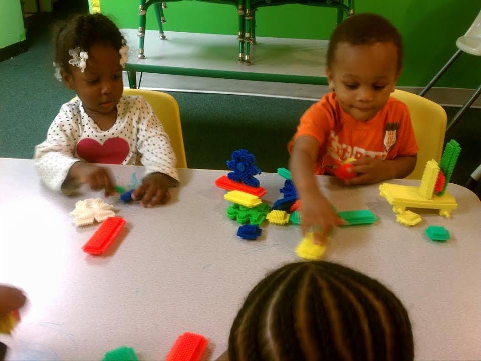 Two children playing with colorful blocks at a table