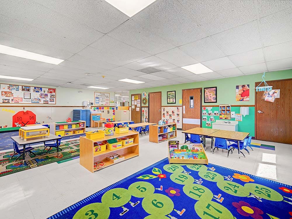 Colorful classroom with small tables, chairs, and play mats