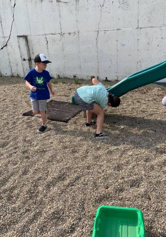 Two children playing on a playground with a slide