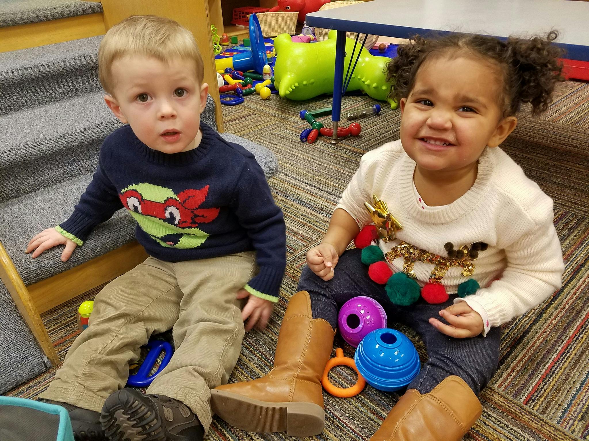 Two children sitting on the floor with toys