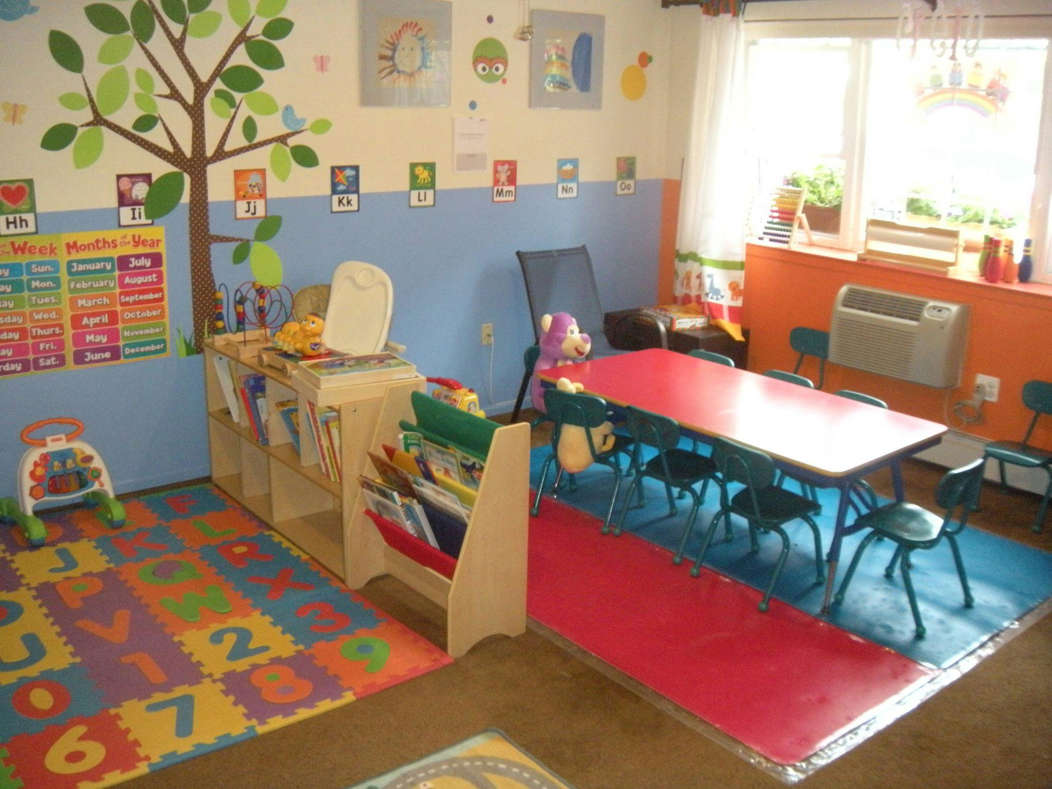 Classroom with colorful alphabet floor mats, small tables, and chairs