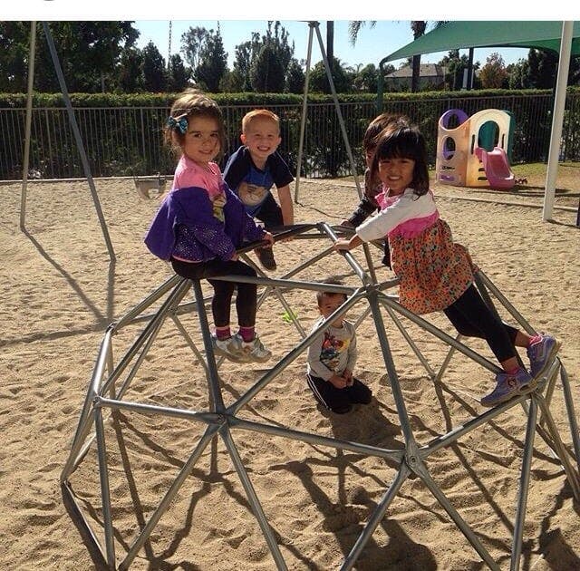 Children playing on a geodesic dome climber at a playground