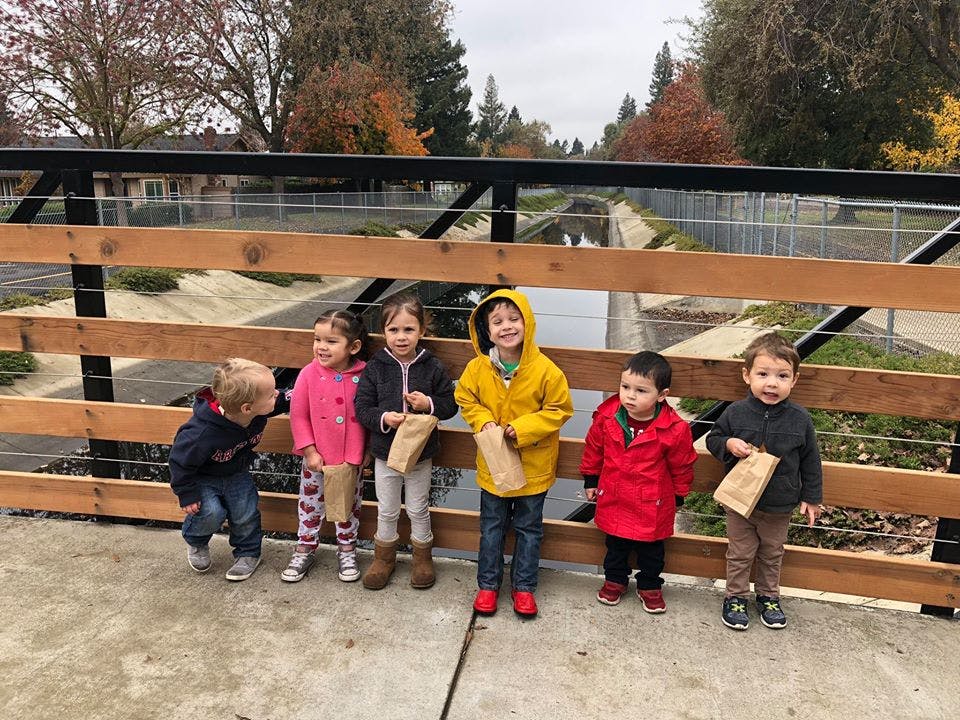 Group of children standing on a bridge holding small paper bags