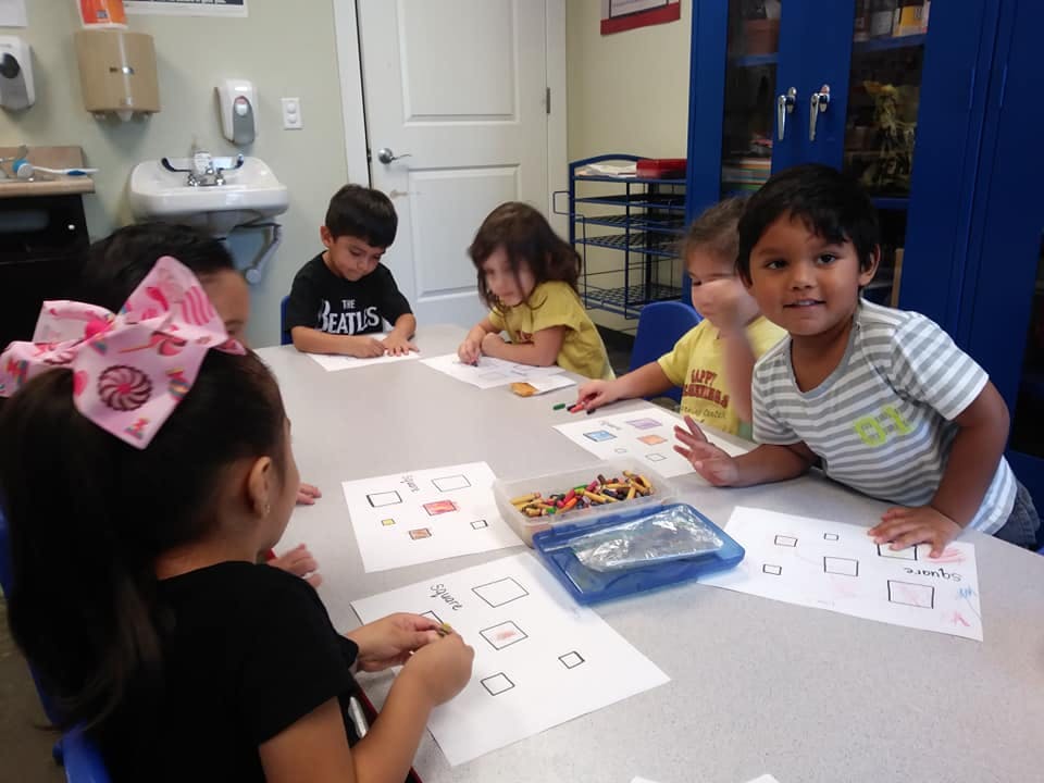 Children sitting at a table doing an activity in a classroom