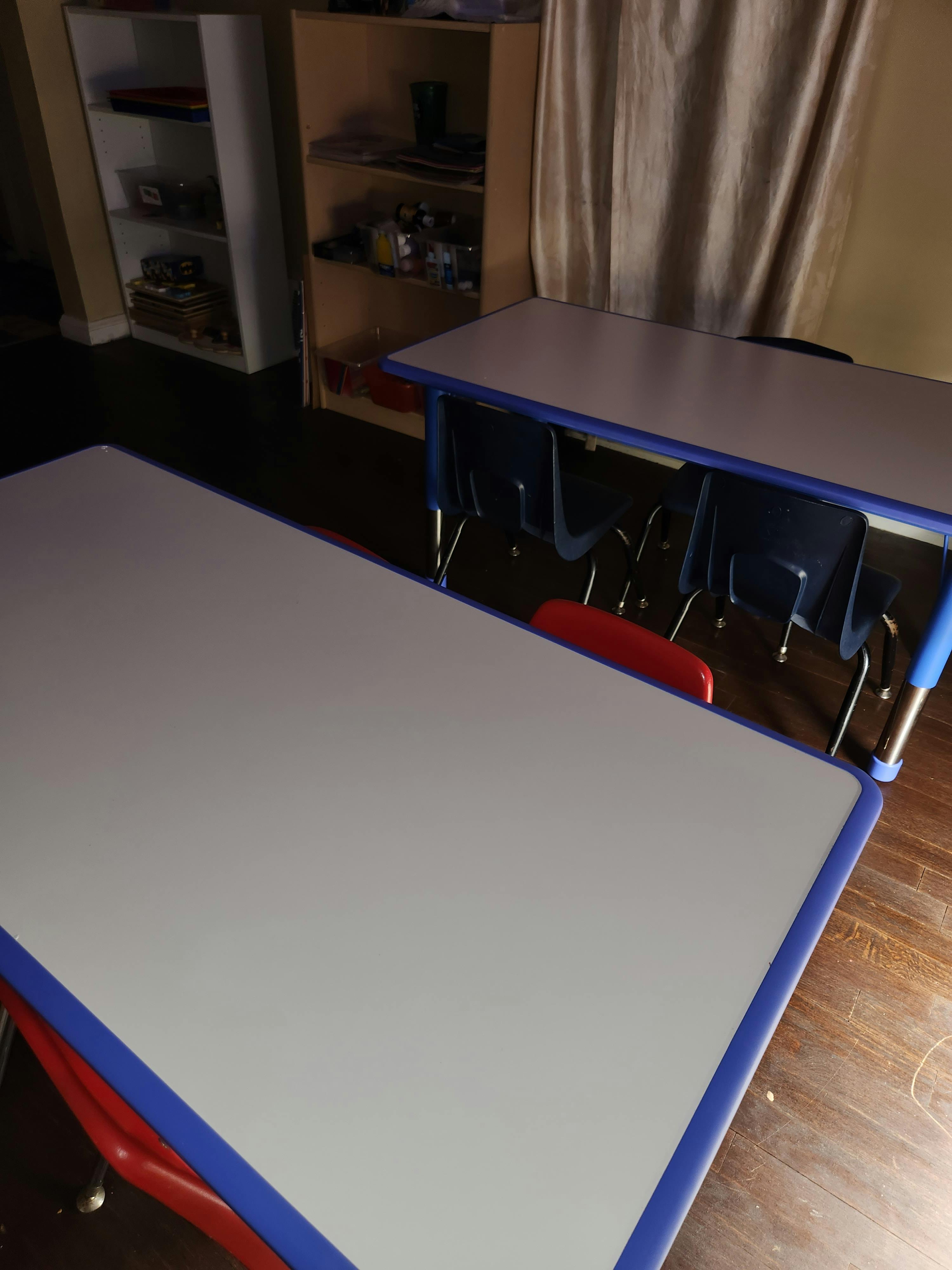 Two empty classroom desks with chairs underneath