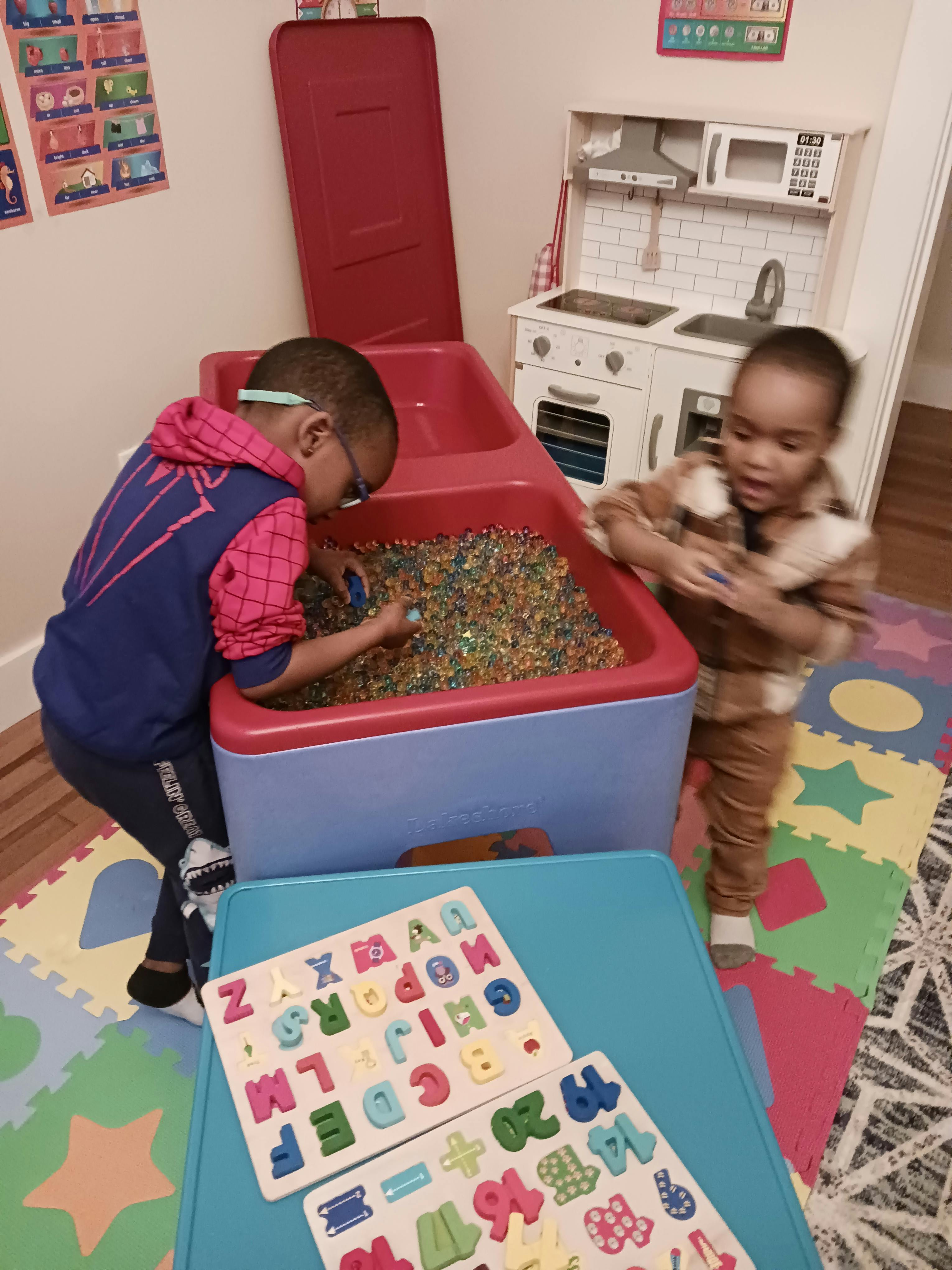 Two children playing with water beads in a sensory bin