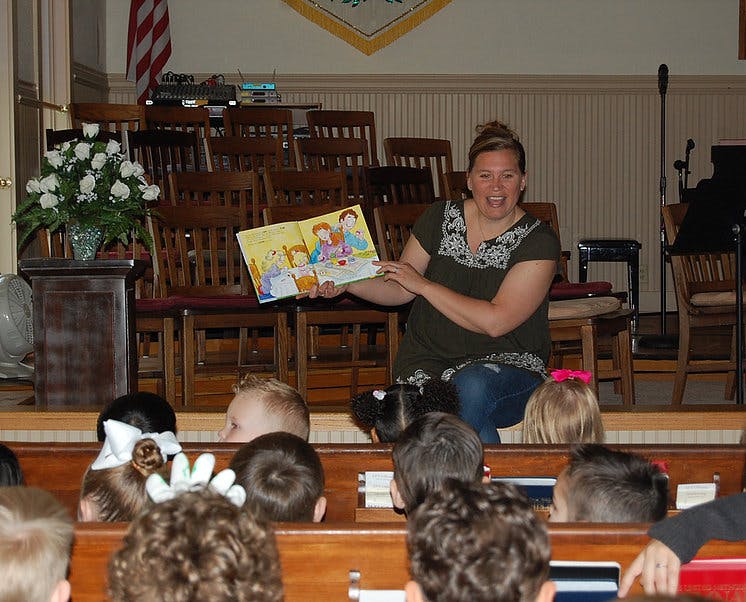 Person reading a book to children