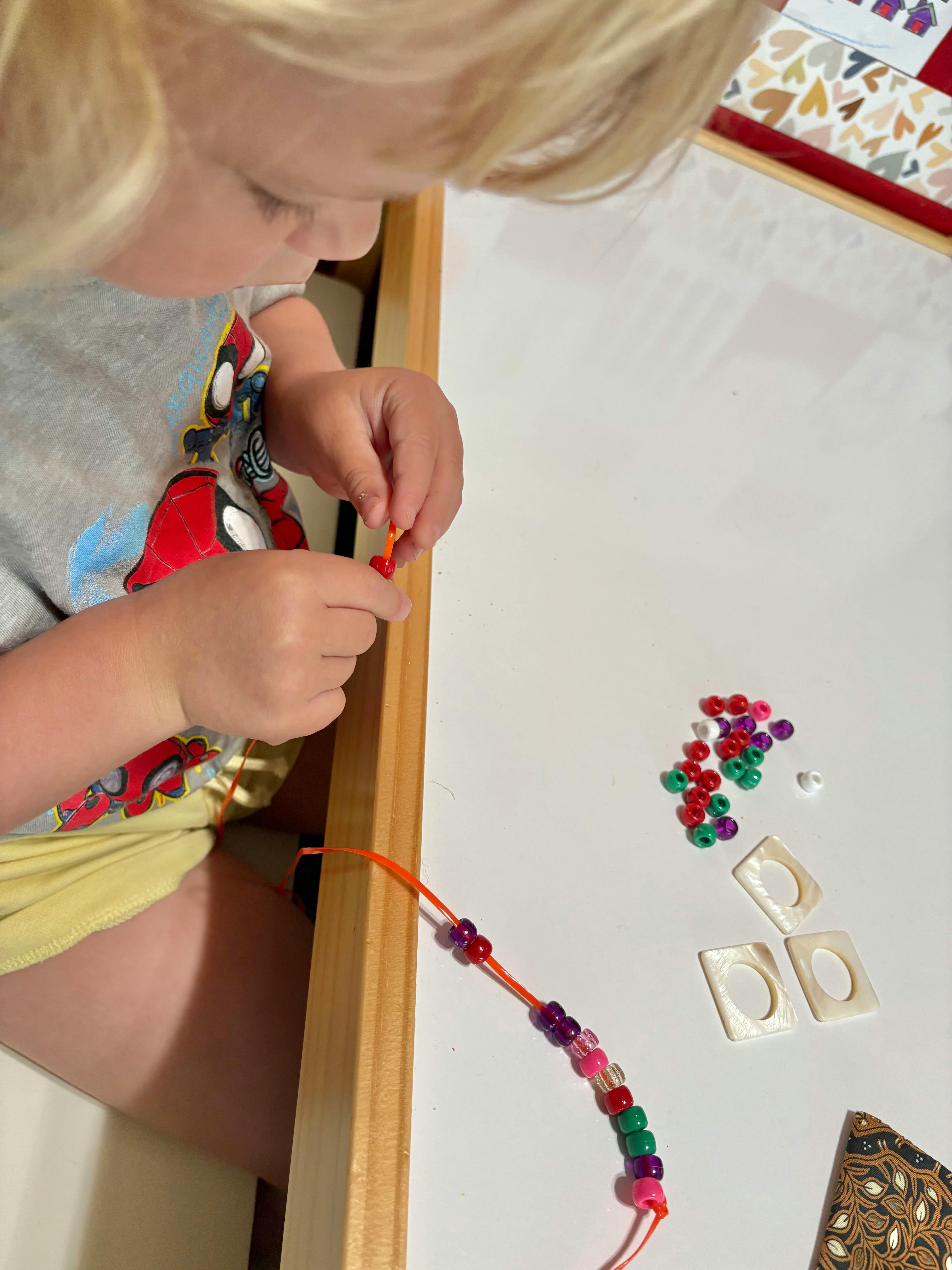 Child stringing beads onto a cord