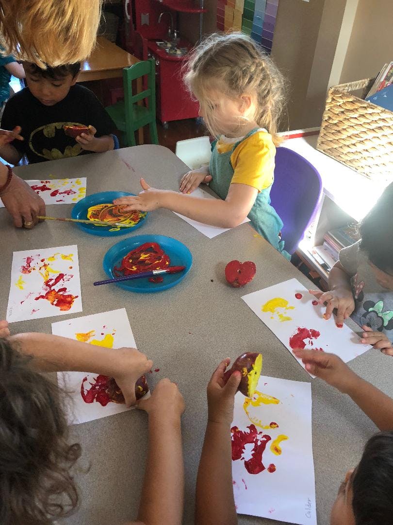 Children doing apple printing art at a table