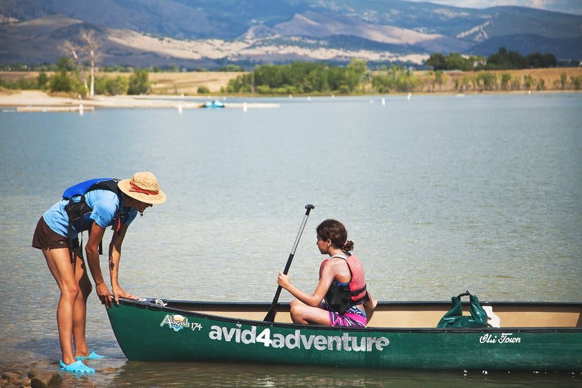Person helping a child in a canoe on the water