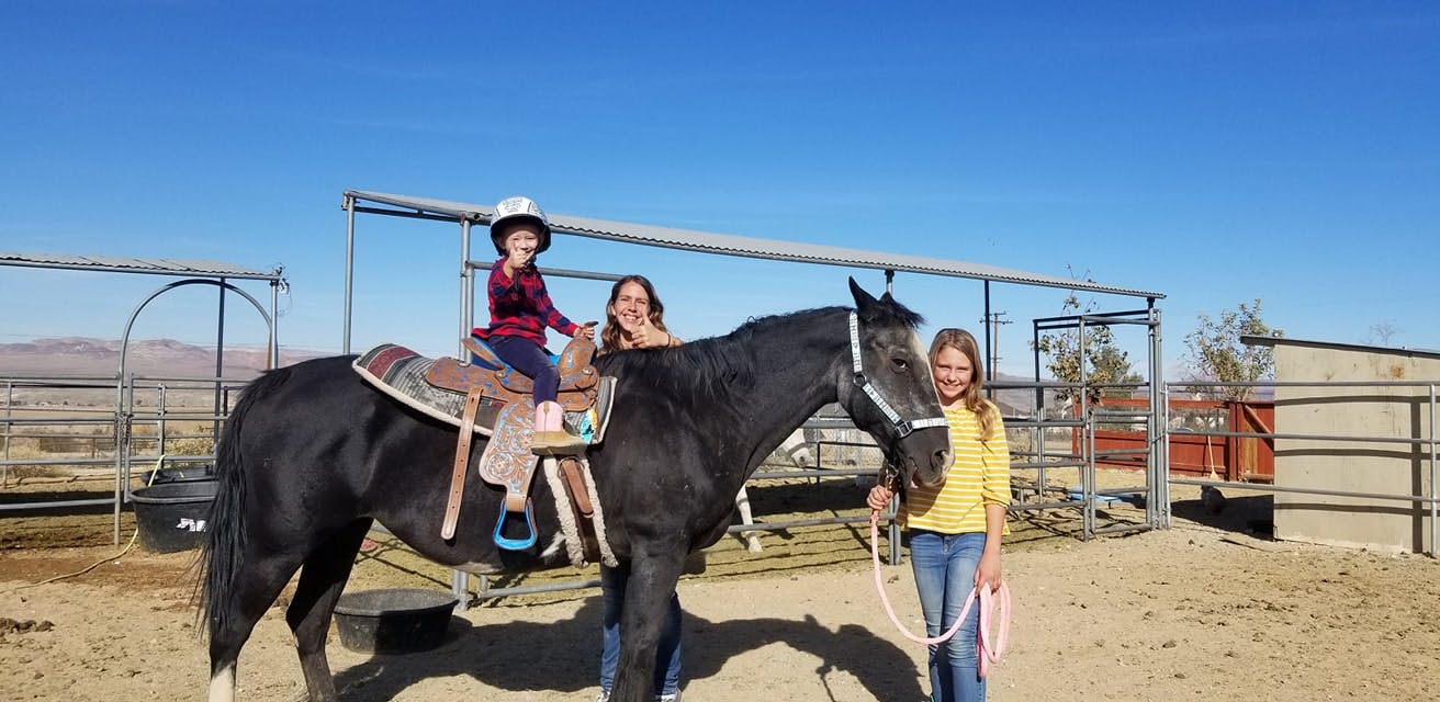 Child on horseback with two people standing next to the horse