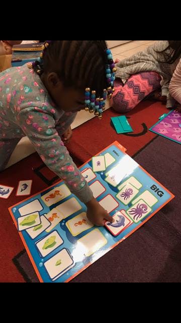 Child playing with a matching game board on the floor