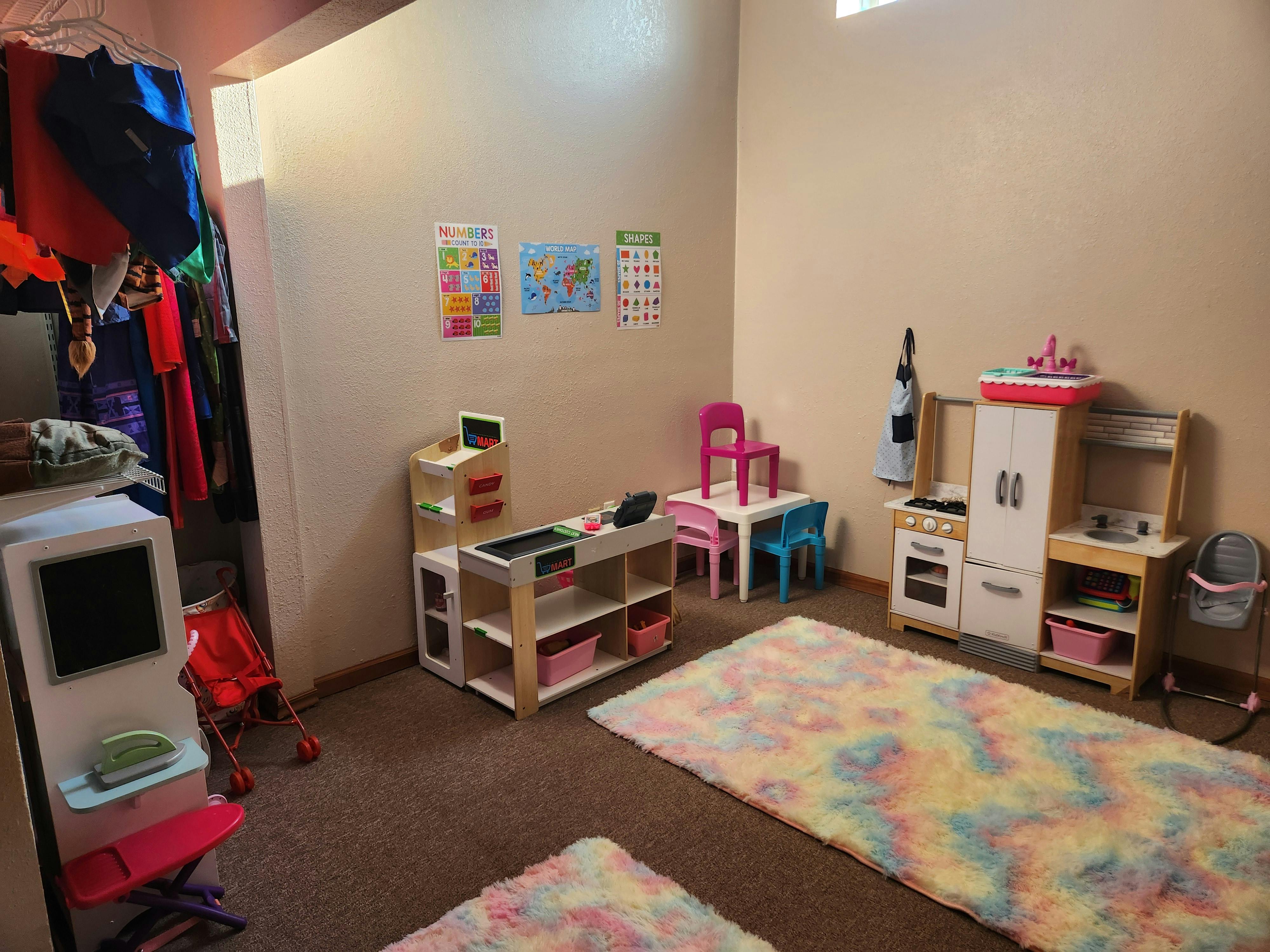Playroom with toy kitchen, table and chairs, and colorful rugs