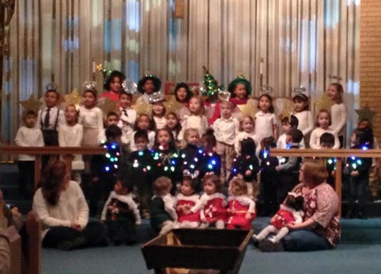 Group of children and adults in a performance, some children wearing lights