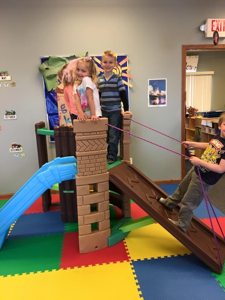 Three children playing on an indoor playground structure