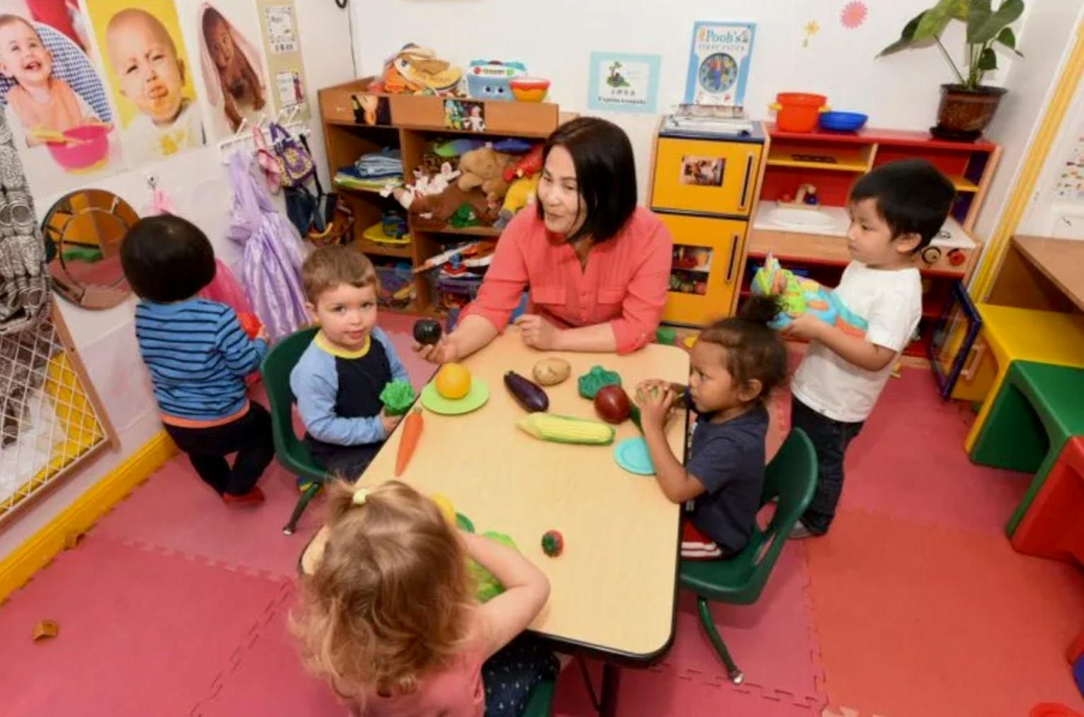 Adult and children playing with plastic toy food in a classroom