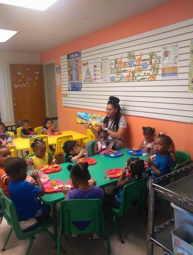 Adult reading to children seated at tables in a classroom