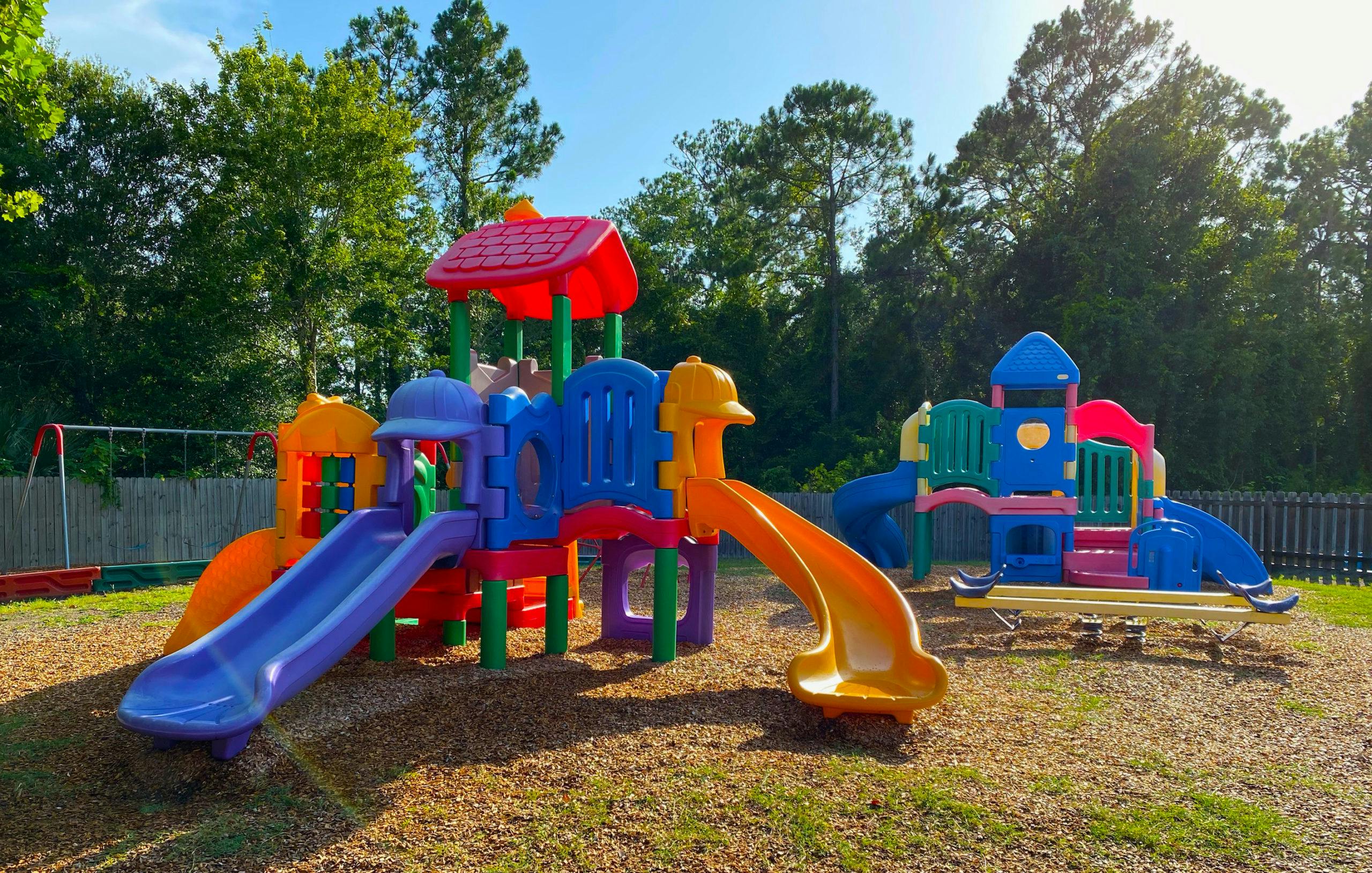 Colorful playground equipment with multiple slides and structures on wood chips