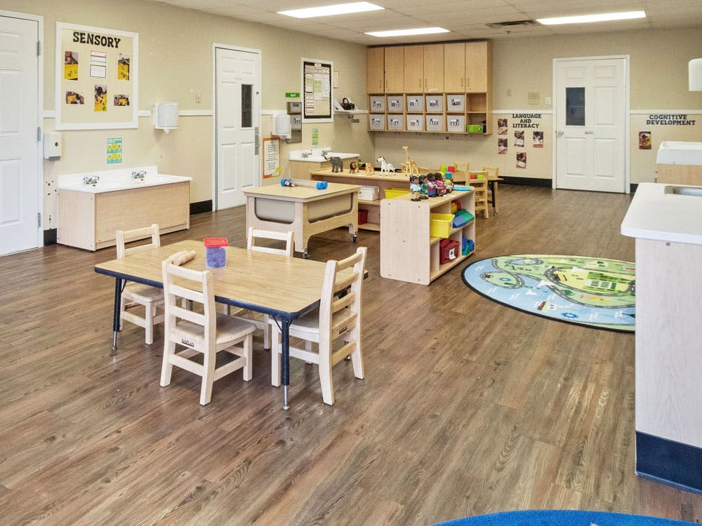 Classroom with tables, chairs, cabinets, and a rug with a road map pattern
