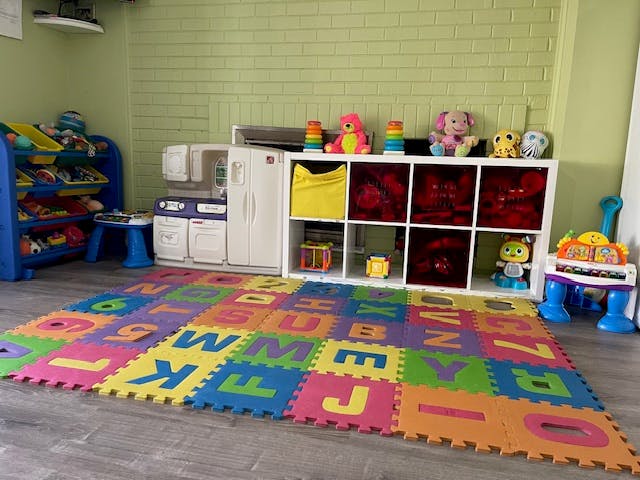 Playroom with alphabet mat, toy kitchen, and storage shelves