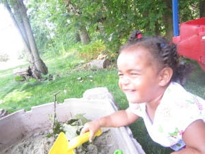 Child playing in a sandbox with a yellow shovel