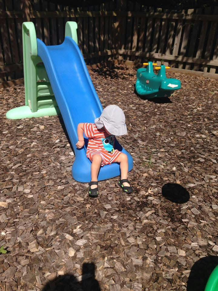 Child sitting on a small slide in a backyard