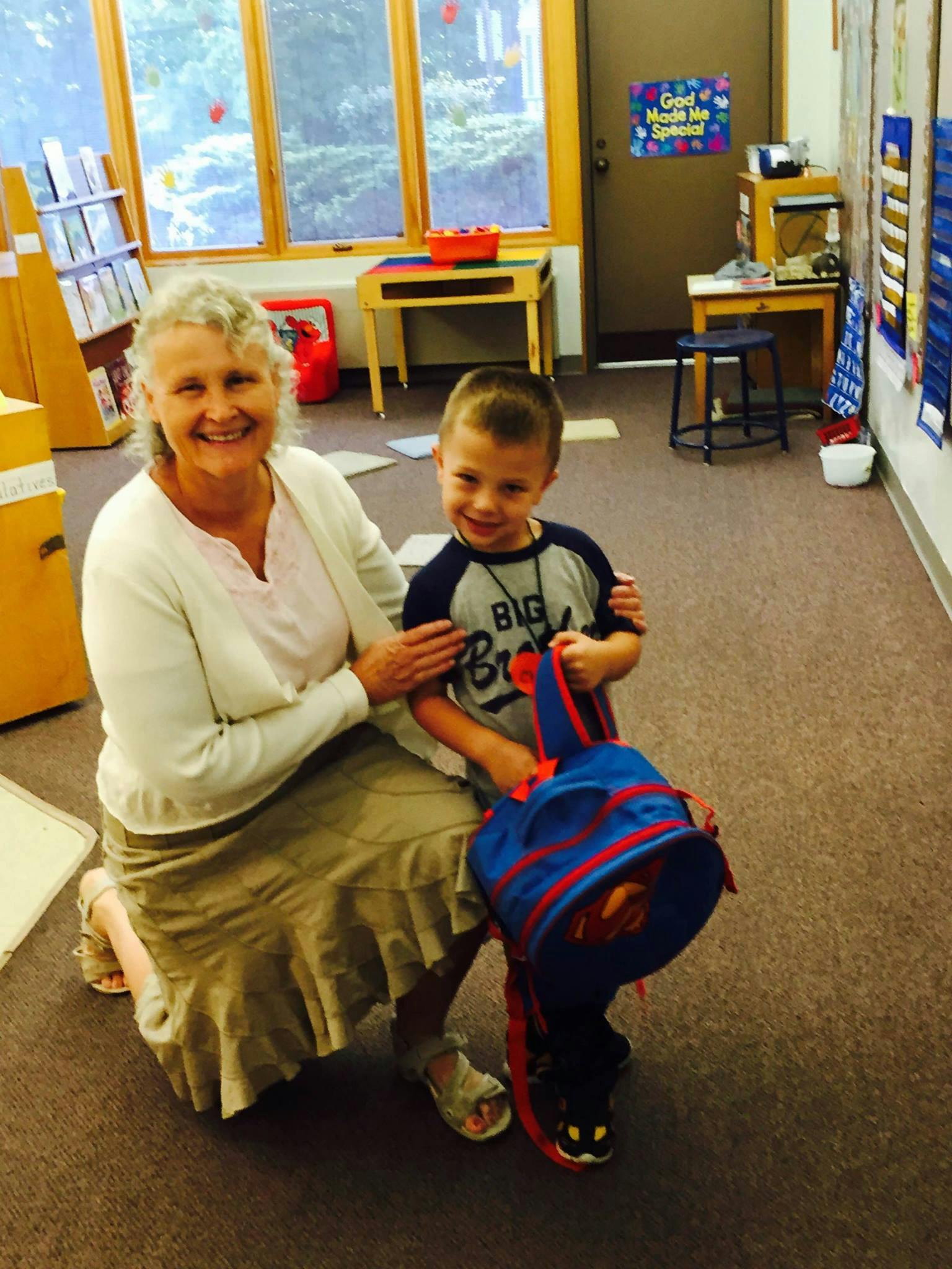 Adult and child posing with a backpack in a classroom