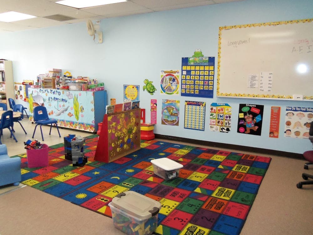 Classroom with colorful rug, chairs, and educational posters on the wall