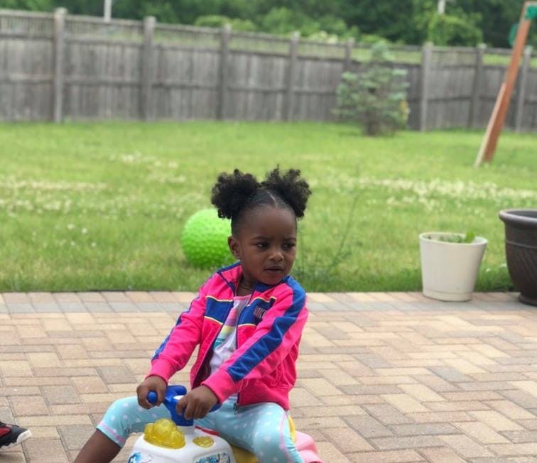 Child riding a toy car on a patio