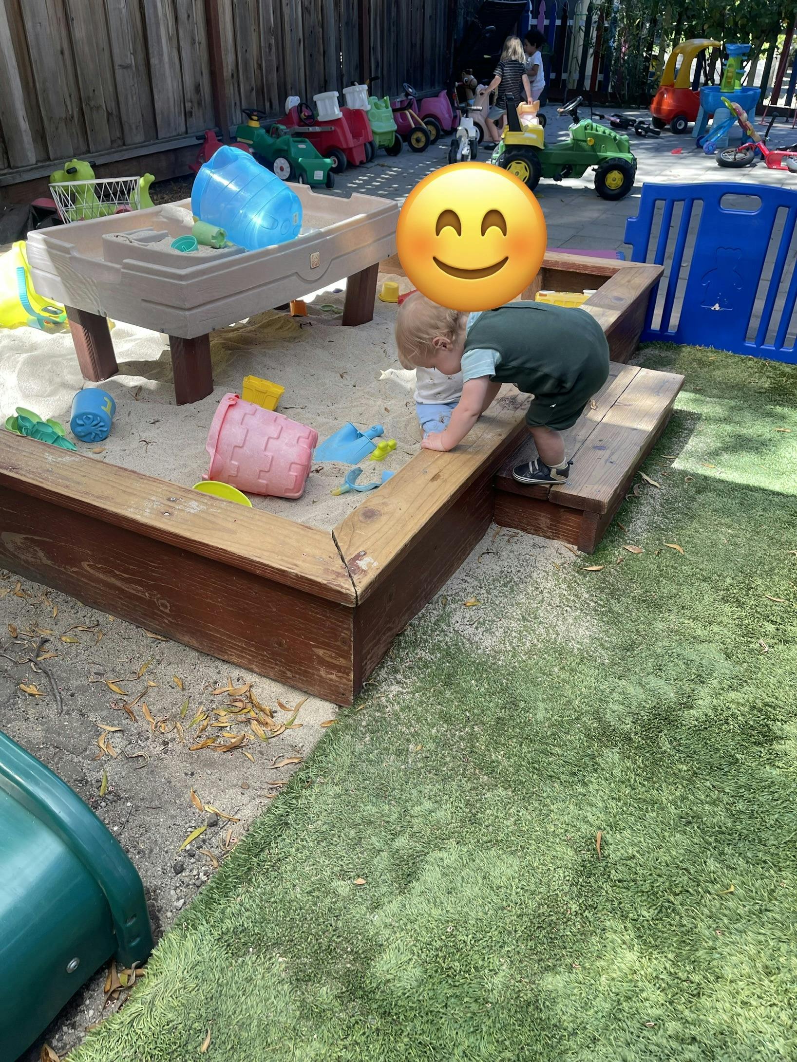 Child playing in a wooden sandbox at a playground