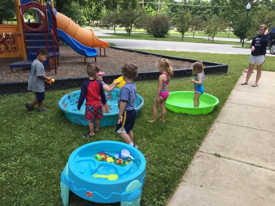 Children playing in wading pools and with a water table outdoors
