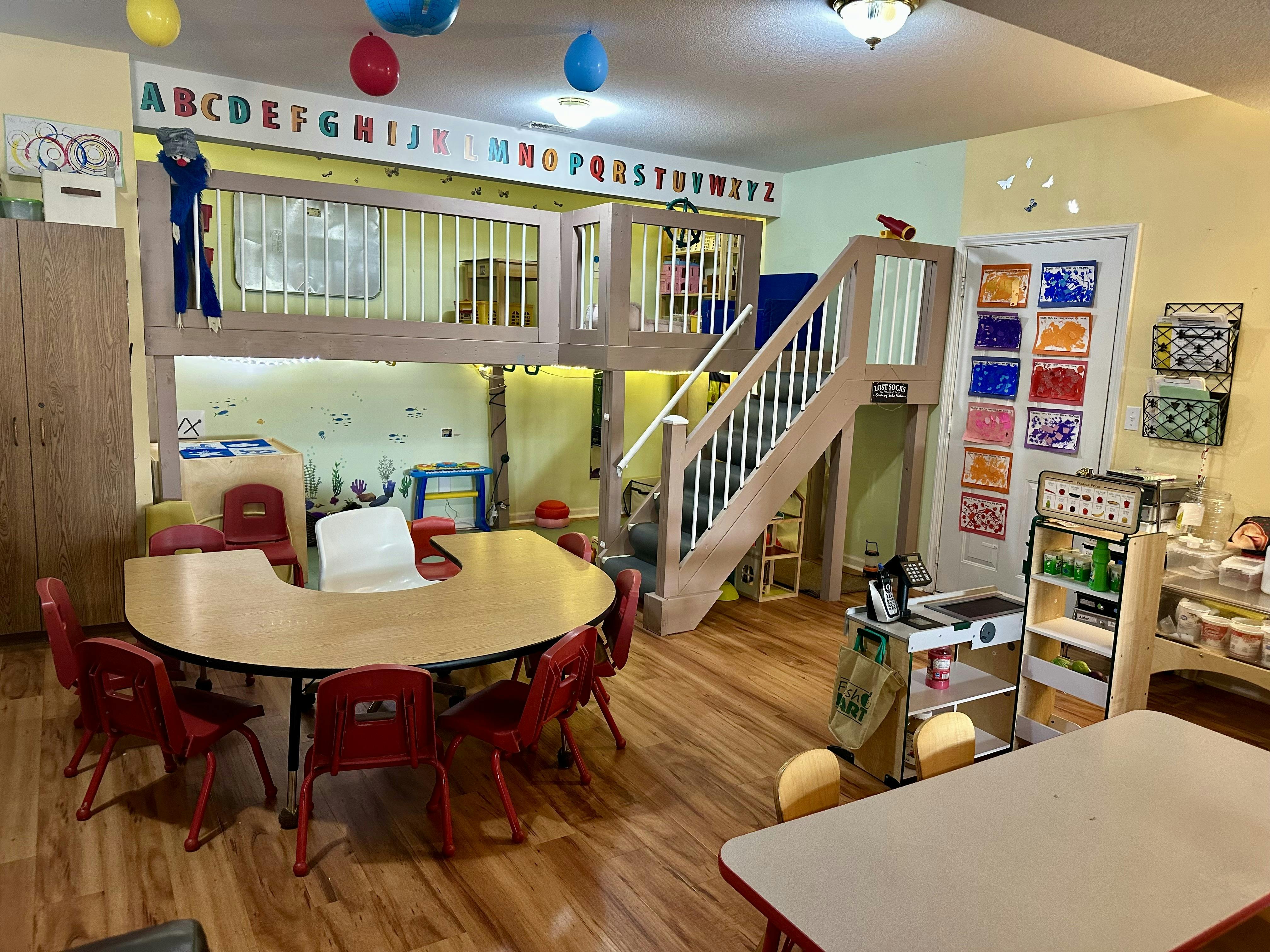 Classroom featuring a loft play structure and a curved learning table